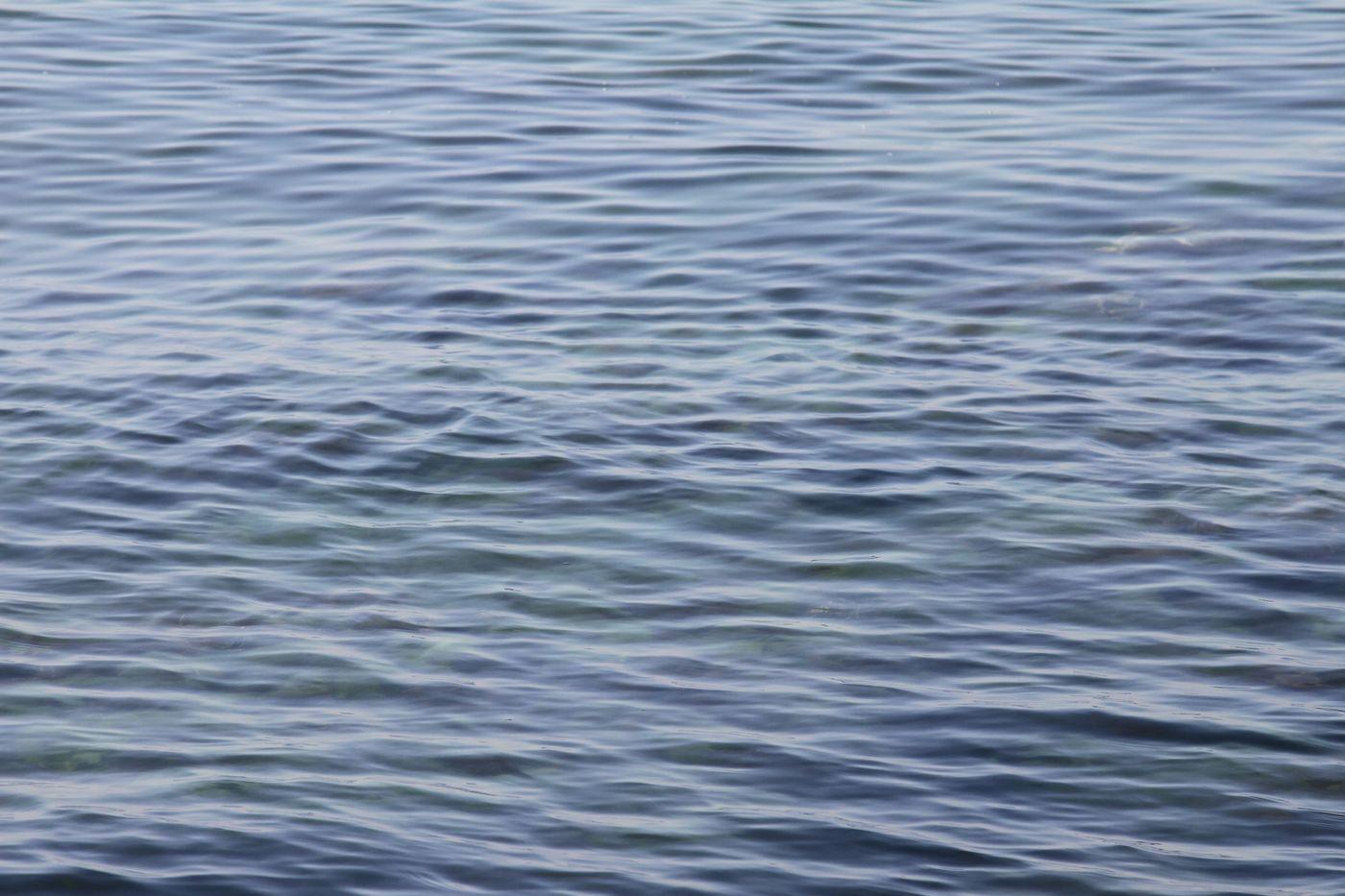 Soft ripple patterns across a calm ocean surface in natural light